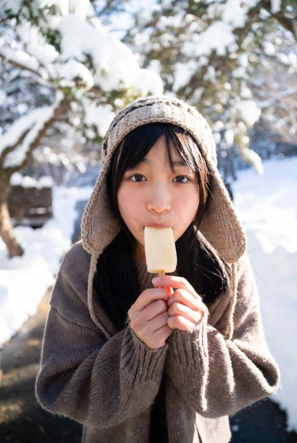 雪の中、アイスを食べる女の子。