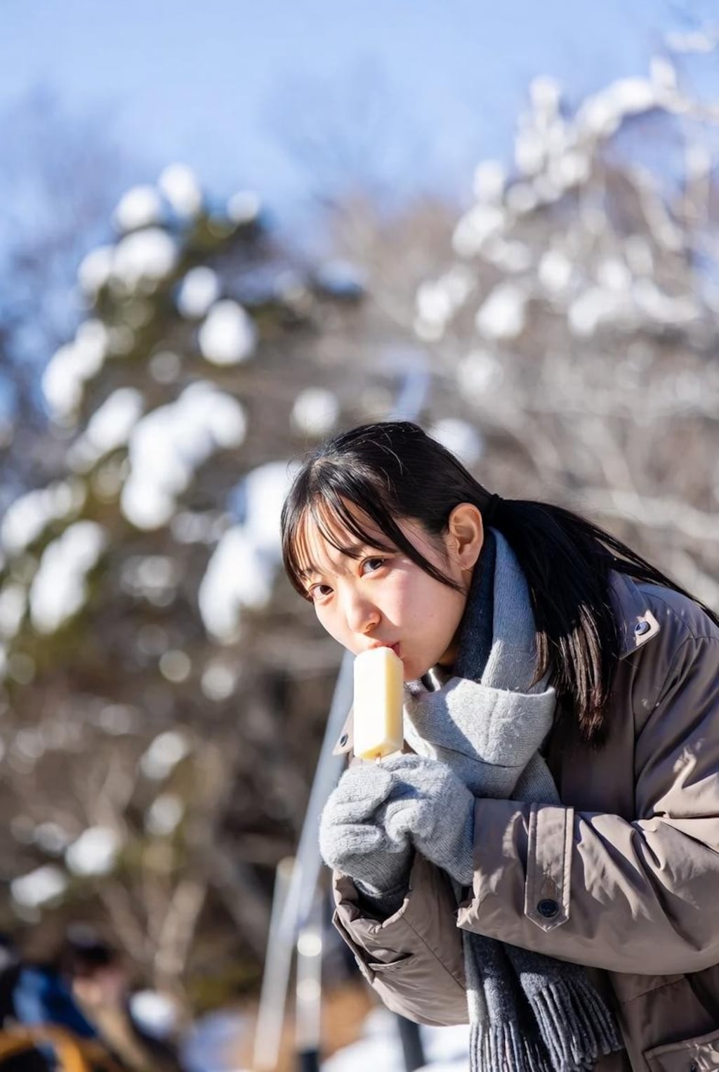 雪の中、アイスを食べる女の子。
