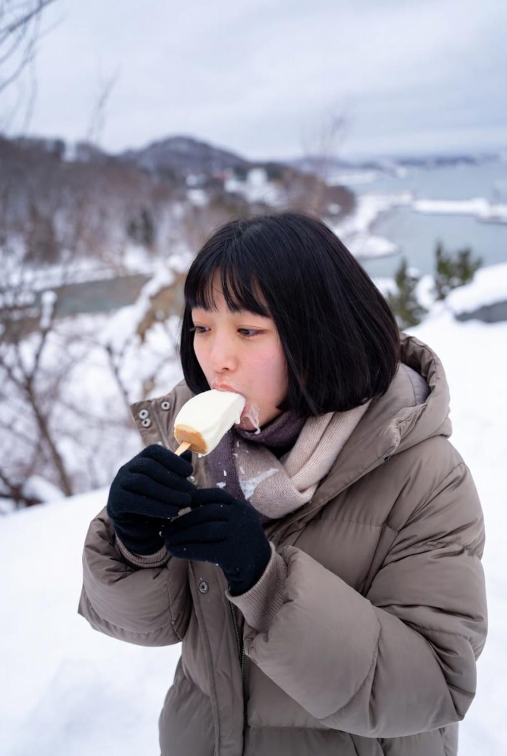 雪の中、アイスを食べる女の子。