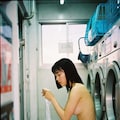 昼間のコインランドリー、自分の服が乾くまで着るものがない20歳日本女性は無着衣で洗濯機の前のイスに座って待ってる 2枚目